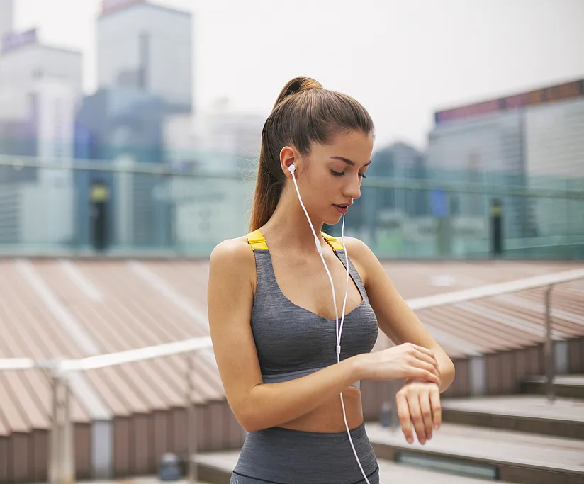 Young woman checking her heart rate monitor after workout in gym, focusing on fitness and health.