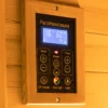 Close-up view of the Wizzisaunas infrared sauna control panel with LCD display showing temperature, timer, and lighting controls, including switches for chromotherapy, reading light, wall light, temperature adjustment, and timer settings.